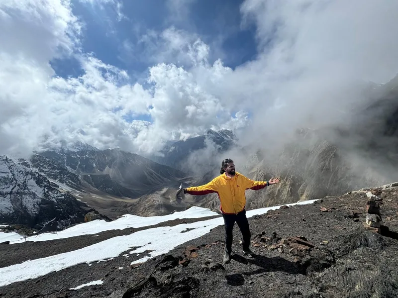 Trekker with arms outstretched above the clouds near Chhipla Kedar