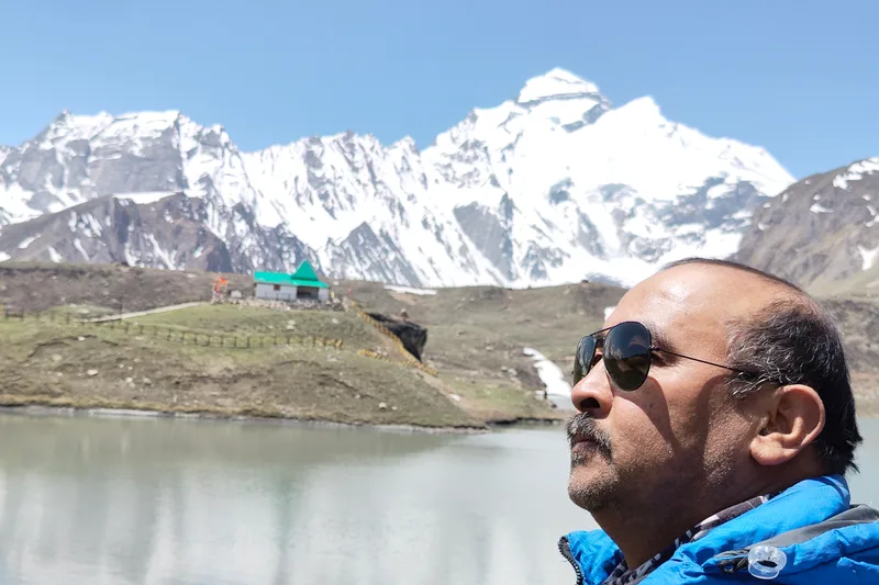 Bashu Panday, founder of The ICE, at a high-altitude lake with snow peaks behind